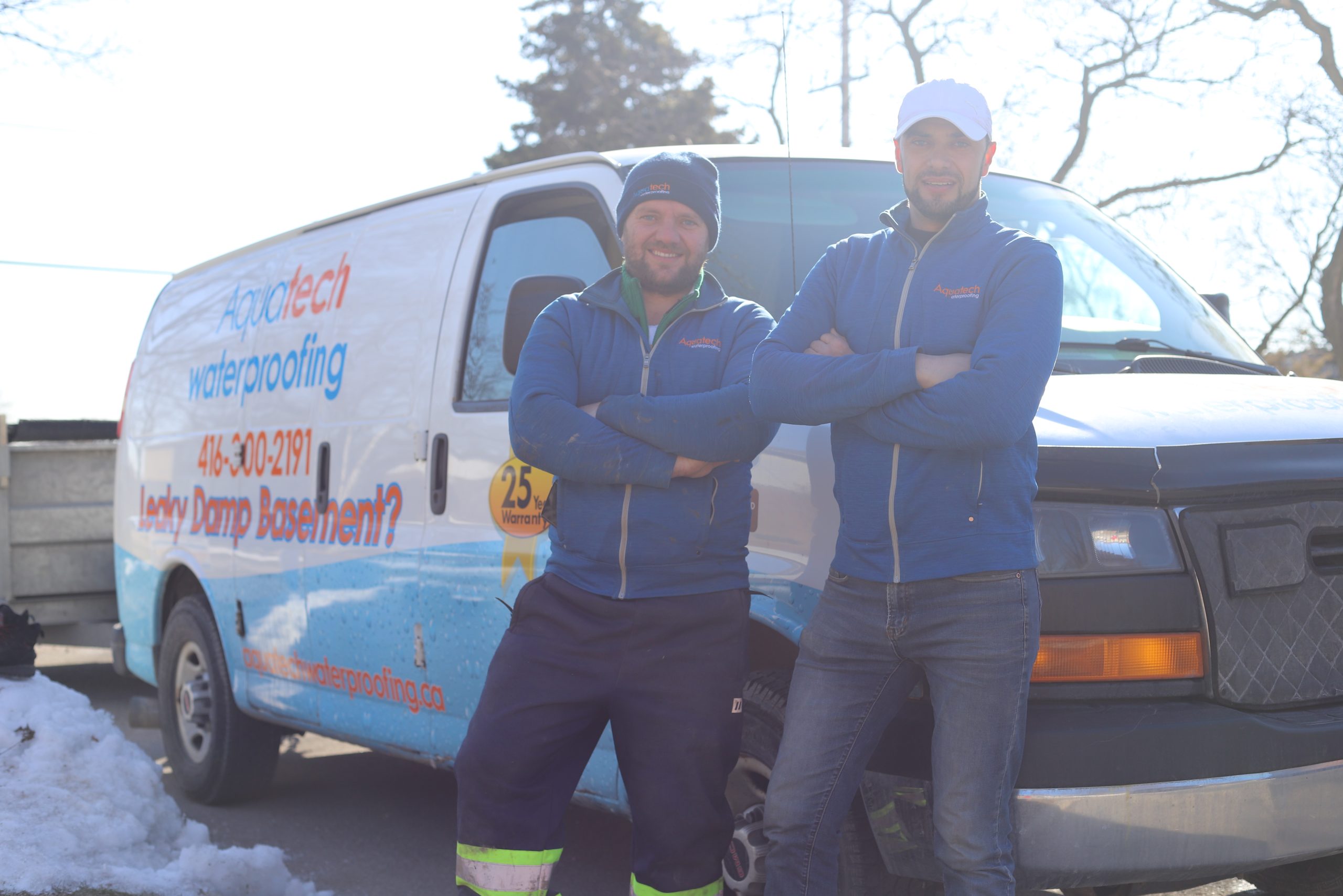 Aquatech Waterproofing staff members posing in front of a company service van
