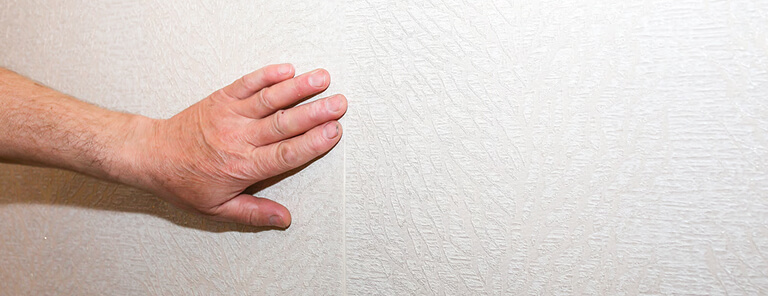 Person testing for structural movement or bowing along a basement foundation wall