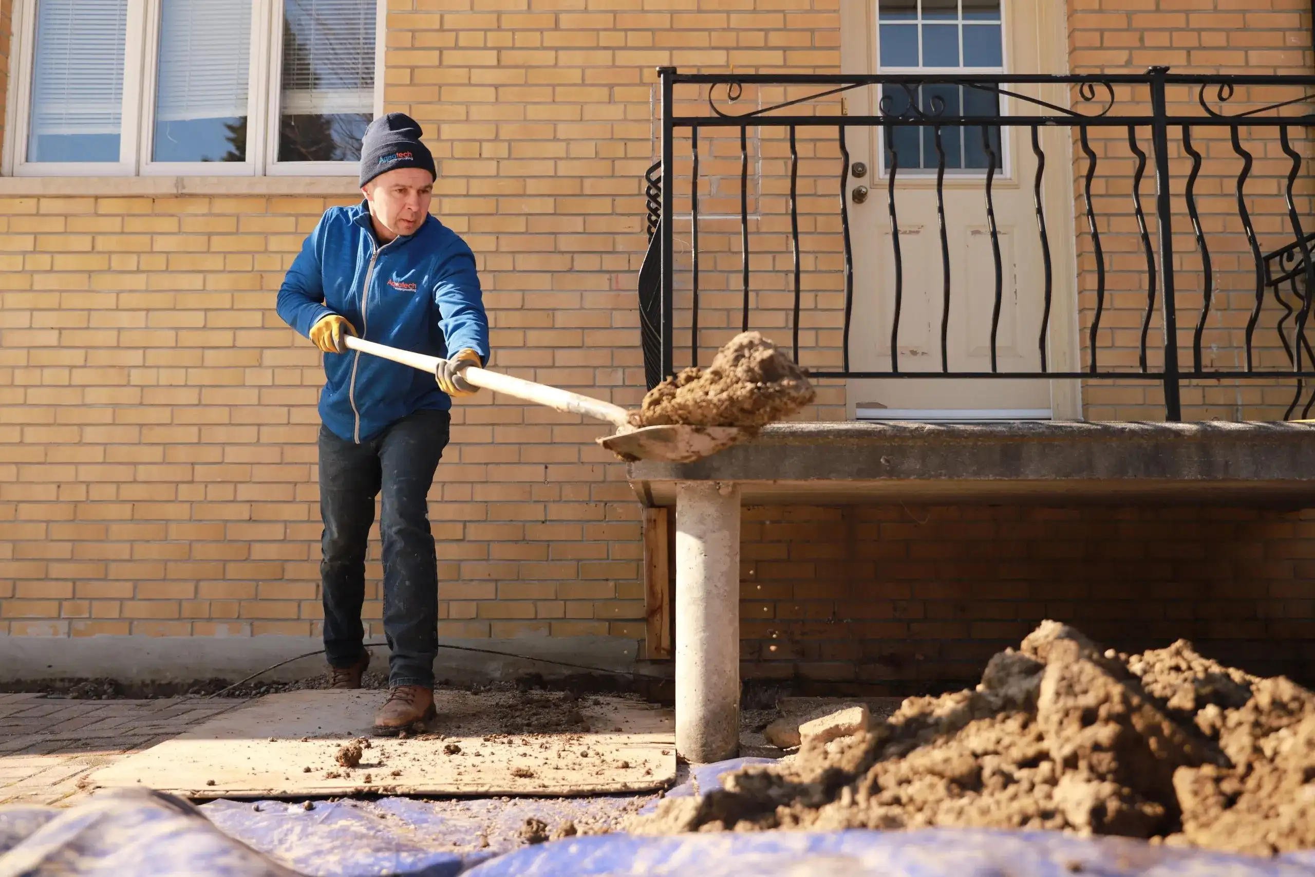 Aquatech technician excavating foundation trench for exterior waterproofing