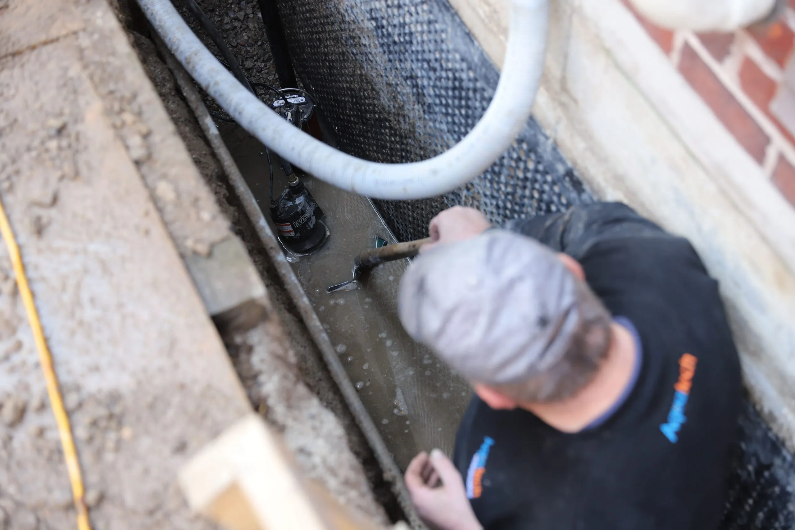 Aquatech technician applying protective coating around foundation piping