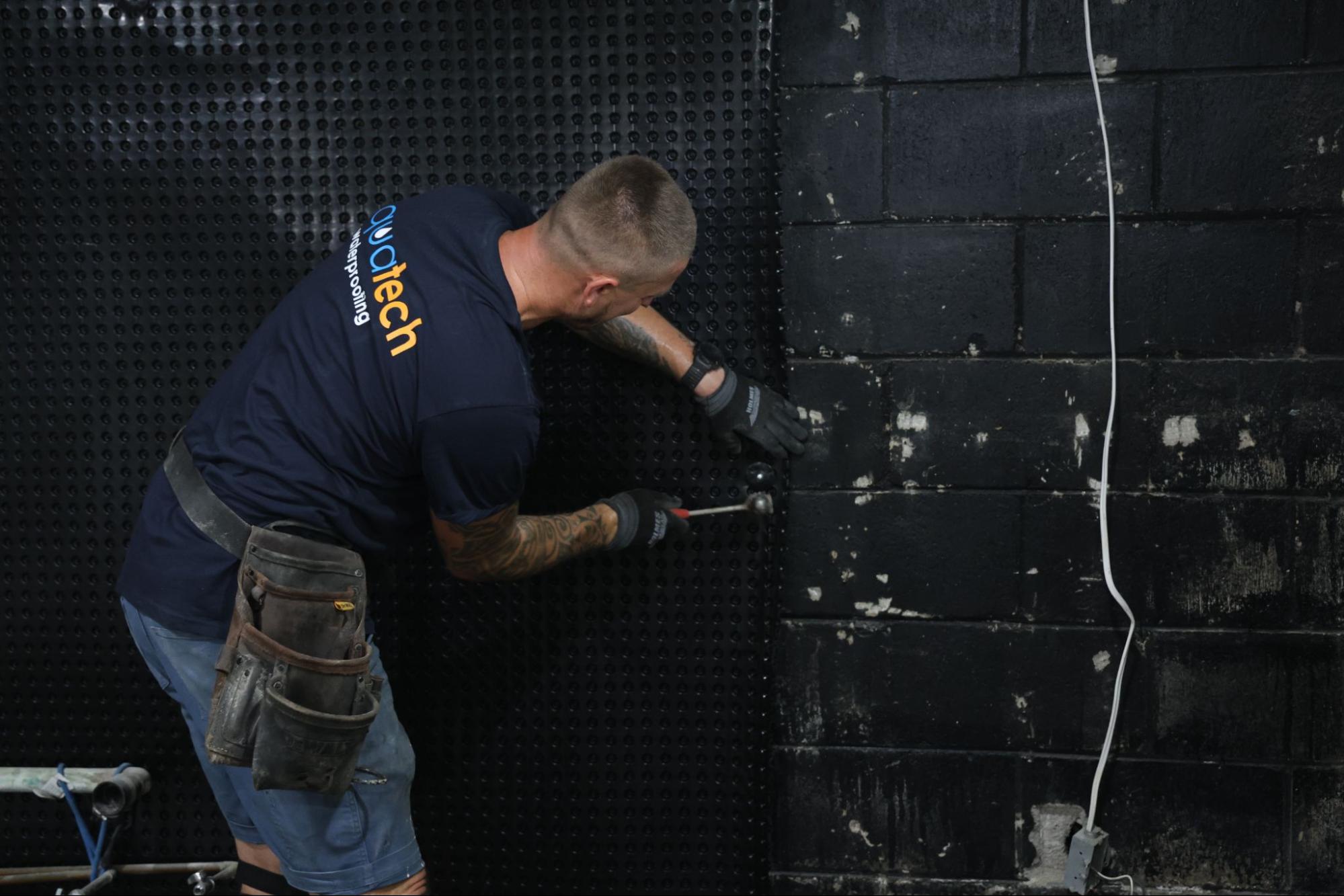 Exterior basement foundation waterproofing with protective membrane and gravel backfill